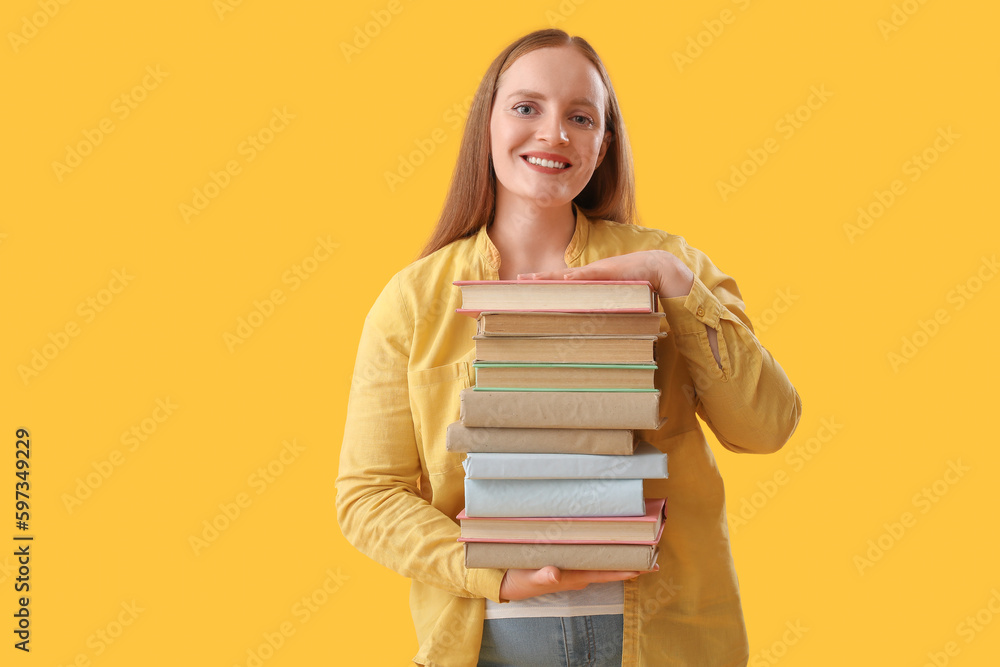 Young woman with stack of books on yellow background