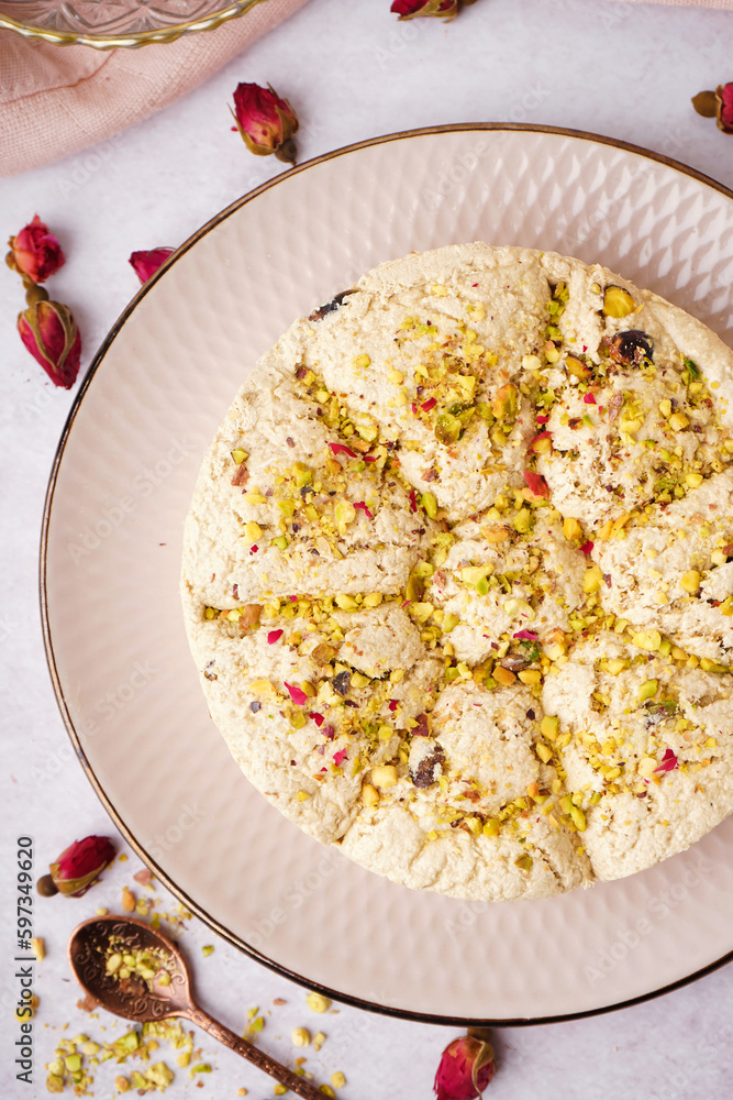 Plate of tasty Tahini halva with pistachios on light background