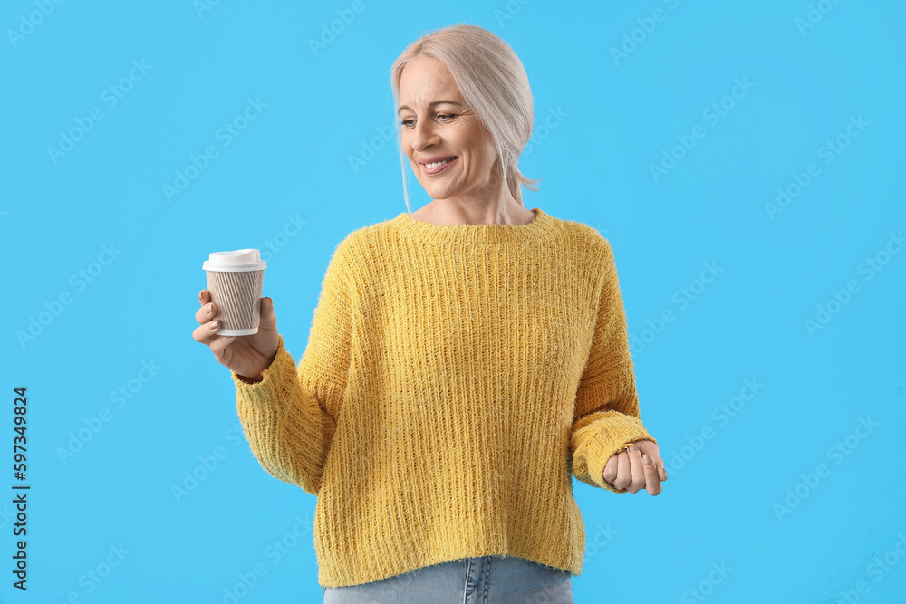 Mature woman with cup of coffee on blue background