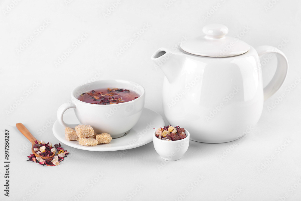 Teapot and cup of fruit tea with snacks isolated on white background