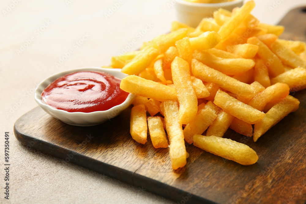 Wooden board with tasty french fries and ketchup on light background, closeup