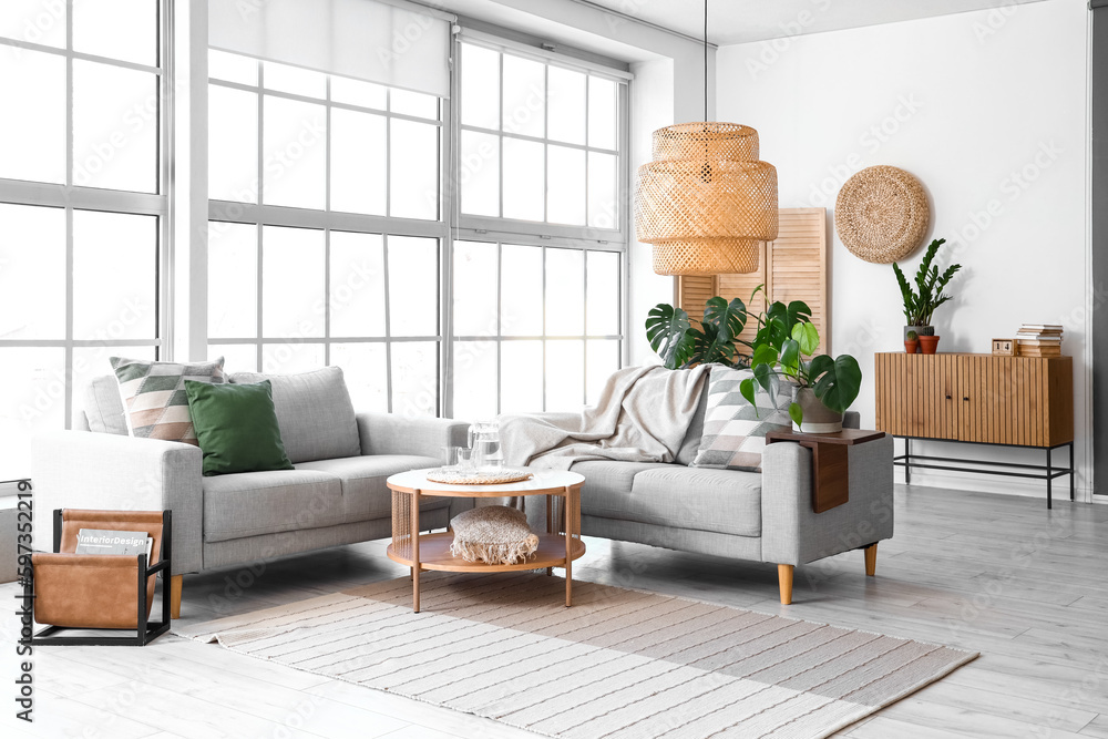 Interior of light living room with sofas and Monstera houseplant