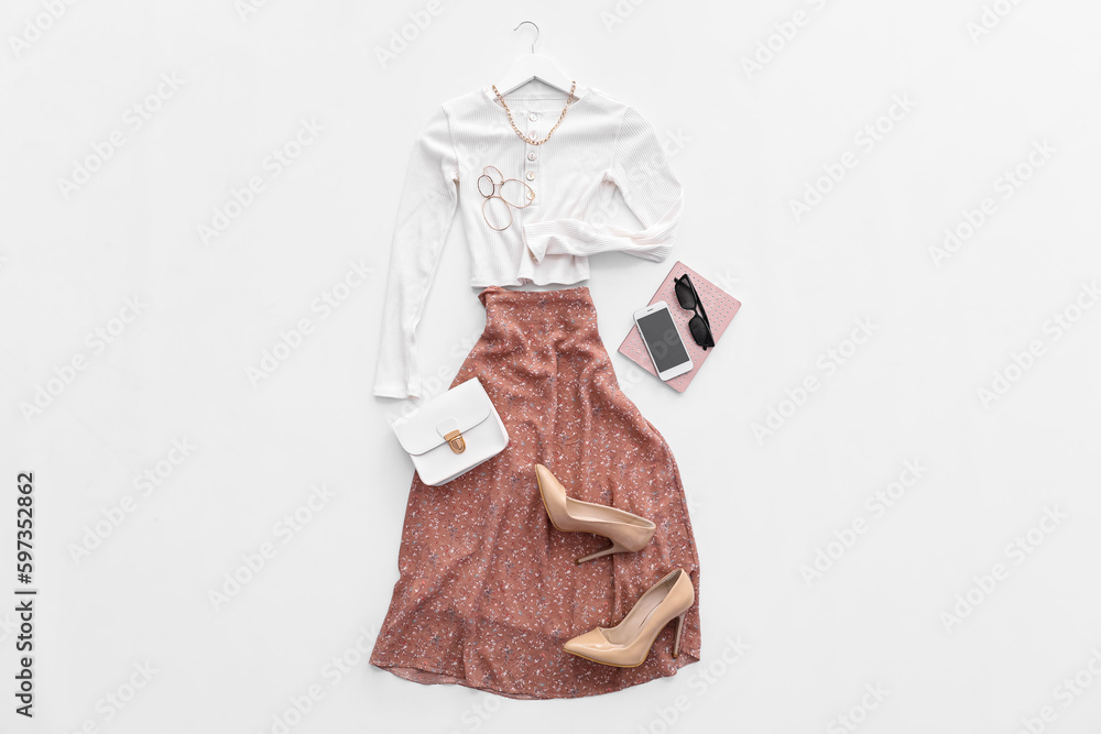 Stylish clothes with accessories, heels, mobile phone and notebook on white background