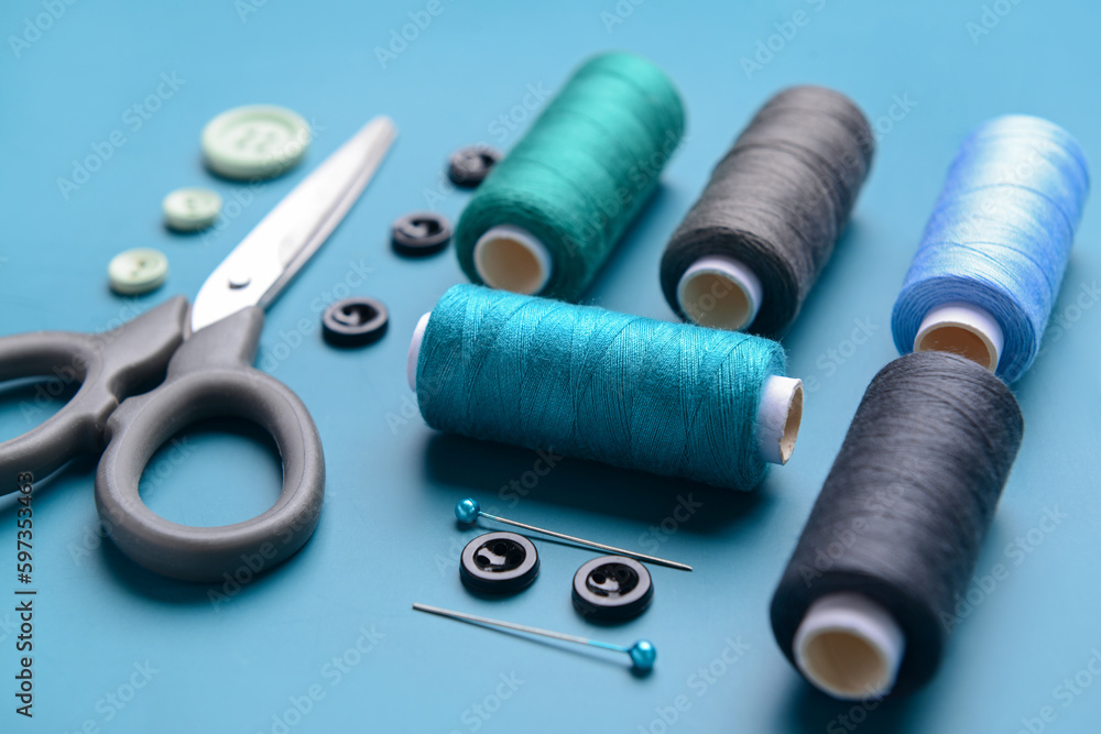 Composition with thread spools, buttons, scissors and ball pins on color background, closeup