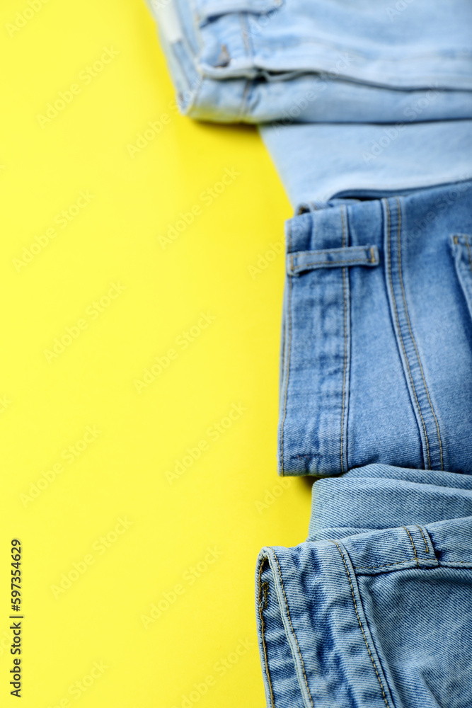 Stylish jeans on yellow background, closeup