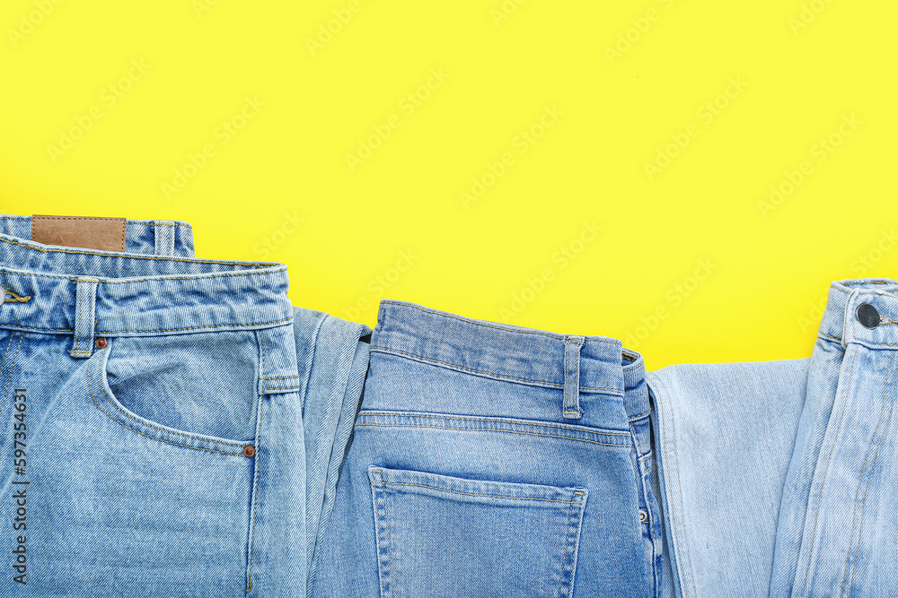 Stylish jeans on yellow background