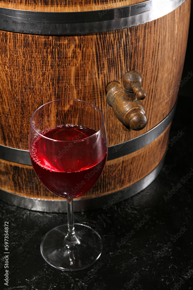 Wooden barrel with glass of wine on dark background