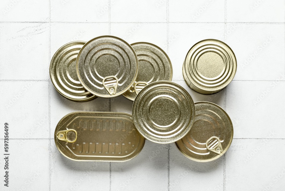 Different tin cans with fish on tiled table