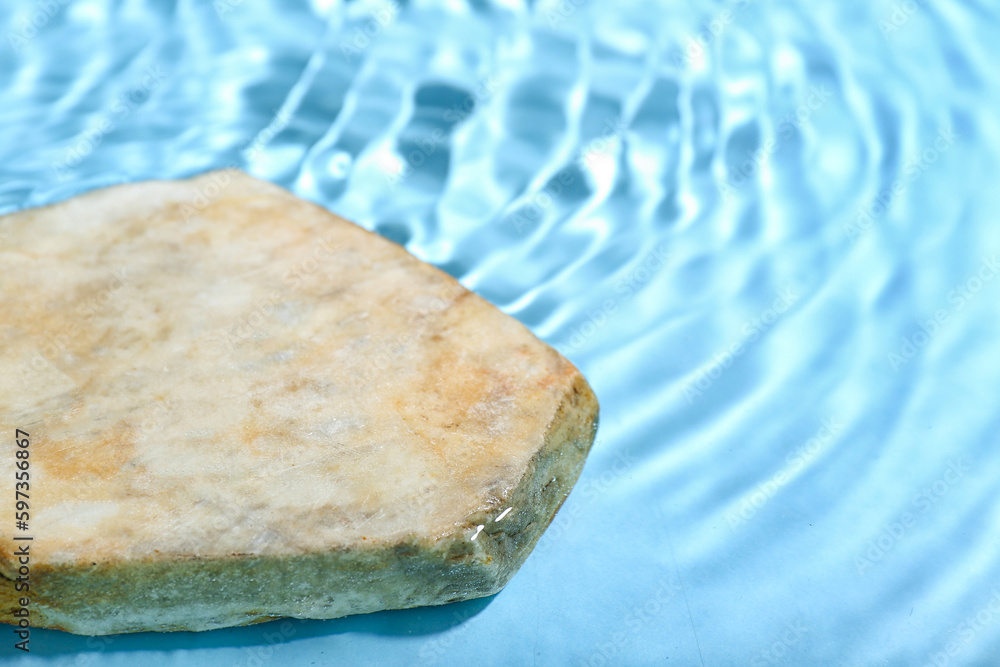 Flat stone in water on blue background