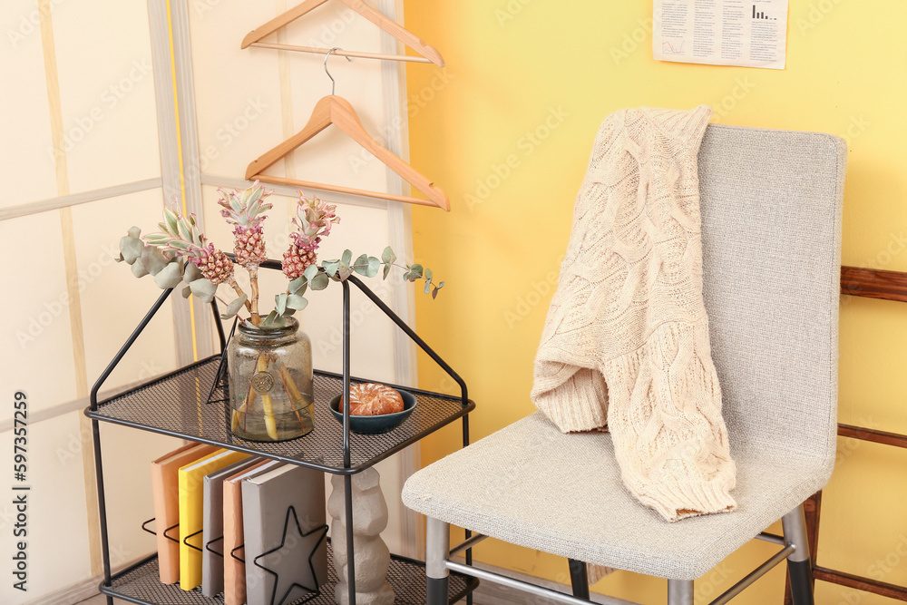 Interior of stylish room with shelving unit, chair and folding screen