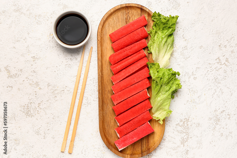 Wooden board with tasty crab sticks and sauce on light background