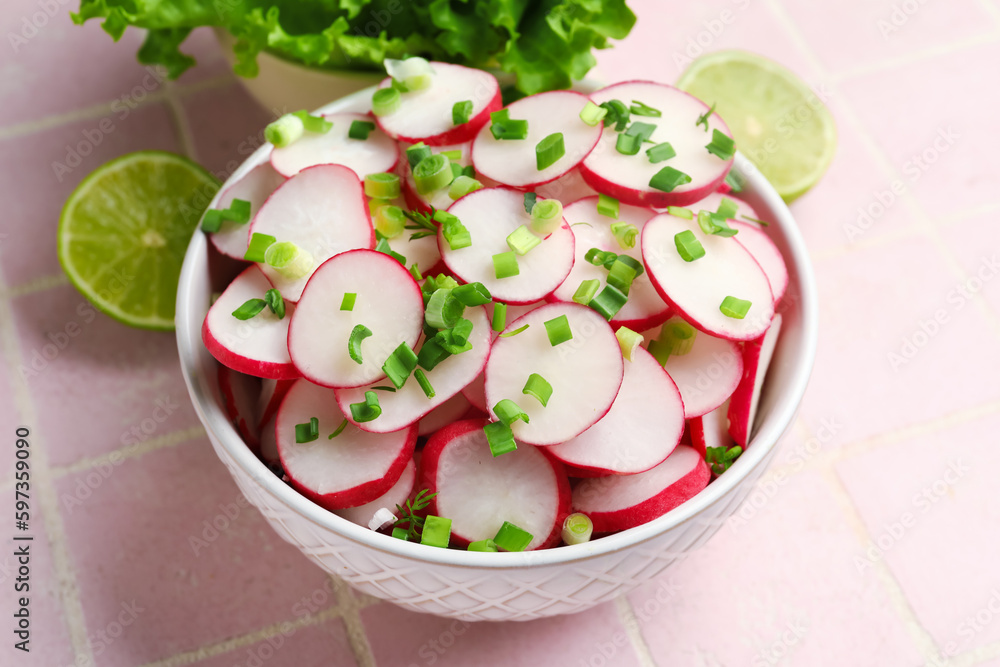 Lettuce and bowl with fresh slices of radish on pink tile background