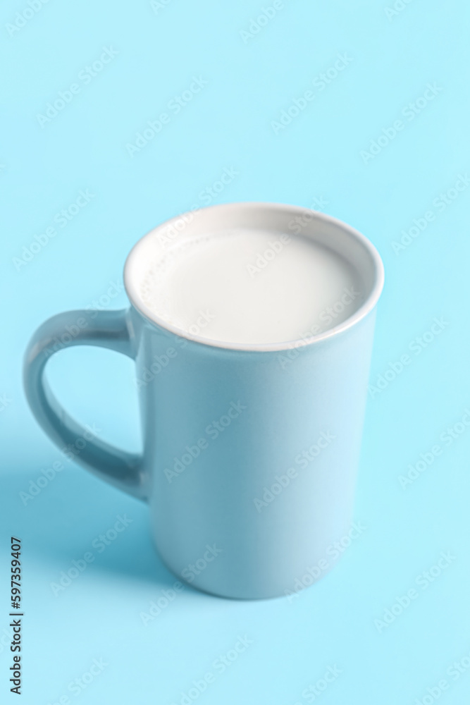 Cup with fresh milk on blue background