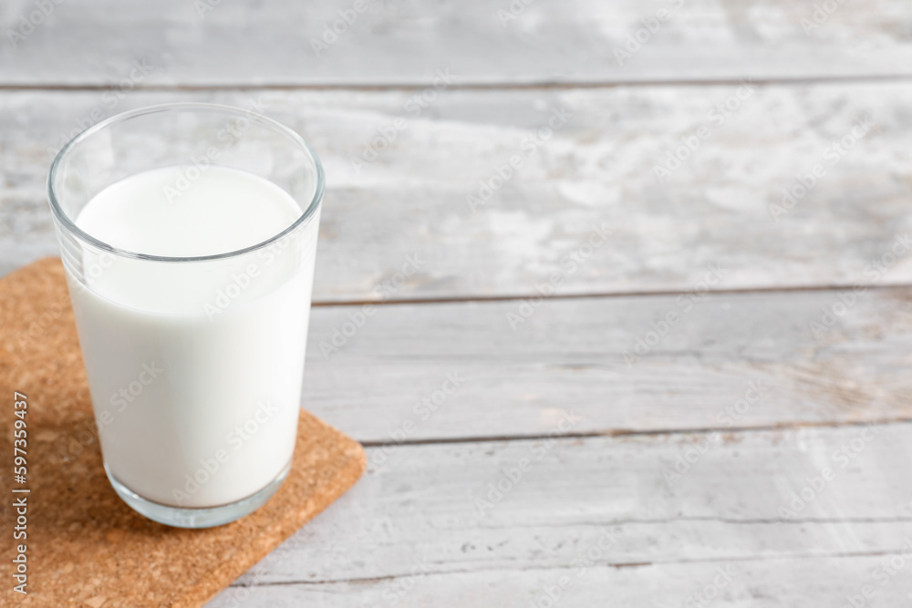 Glass with fresh milk on grey wooden background