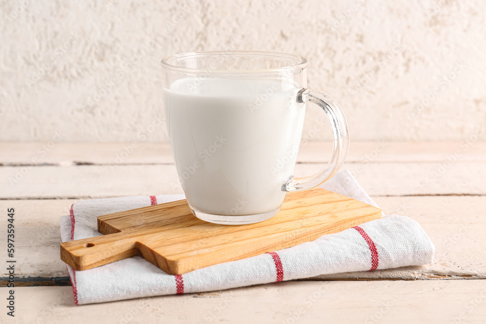 Glass cup with fresh milk on light wooden table