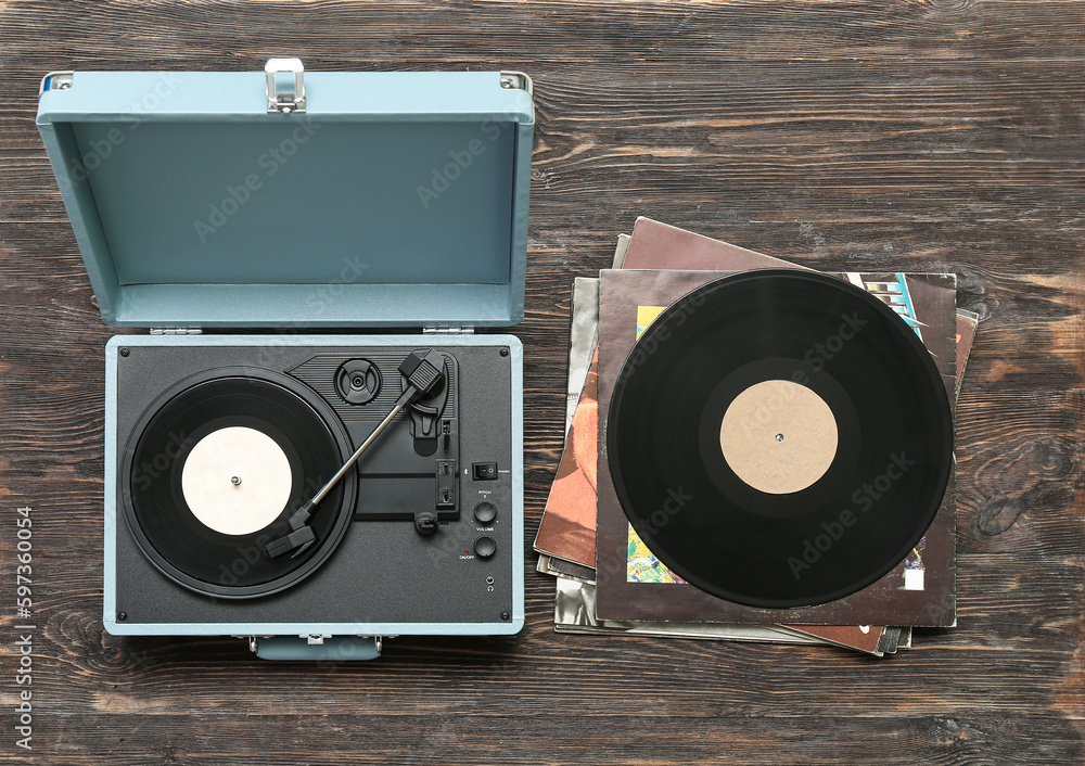 Record player with vinyl disks on dark wooden background