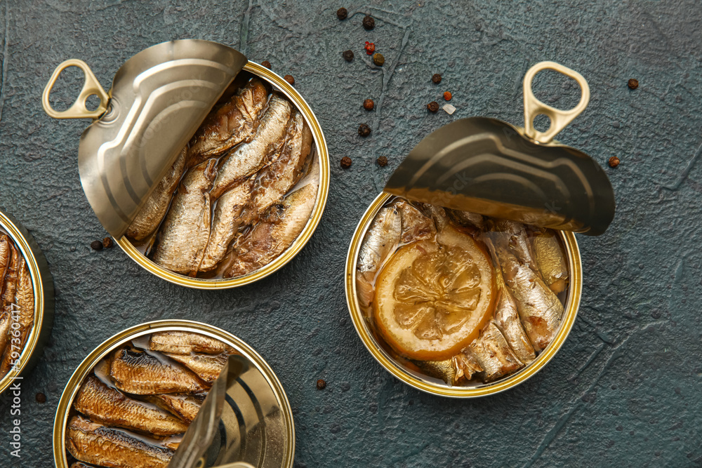 Opened tin cans with sprats in oil on black table