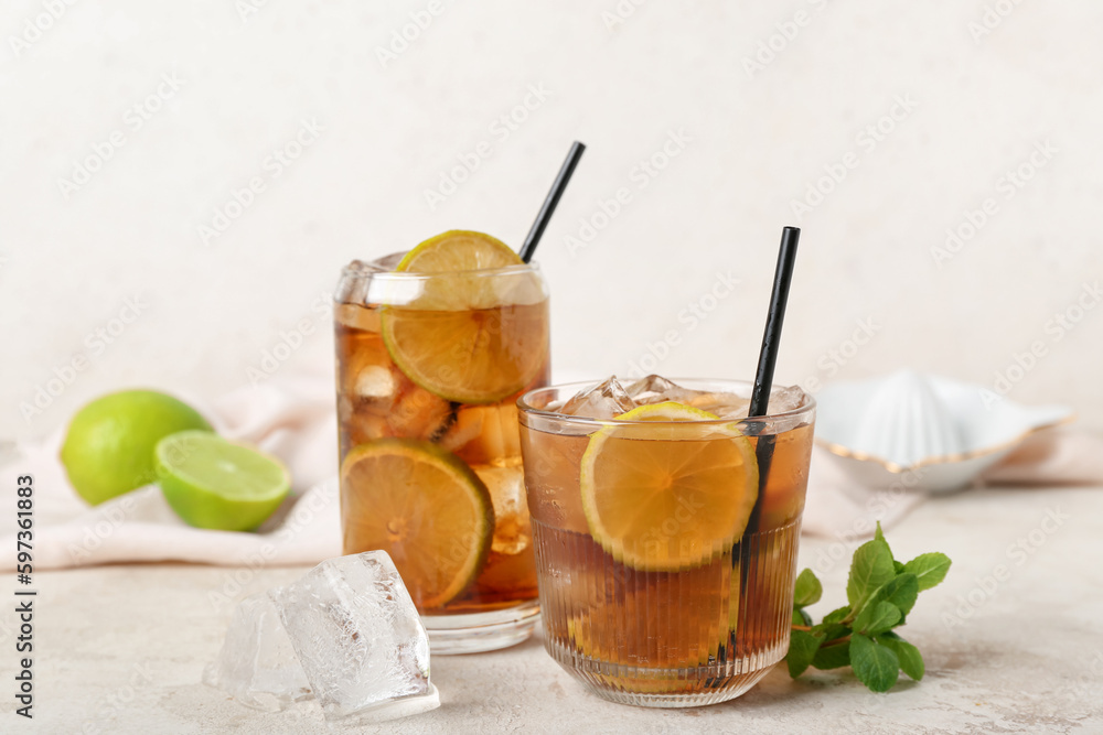 Glasses of tasty Cuba Libre cocktail on light background