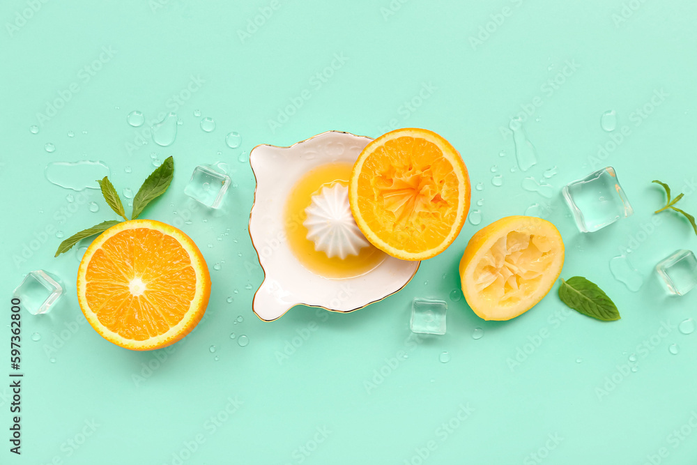 Juicer with orange slices, ice cubes and mint on turquoise background