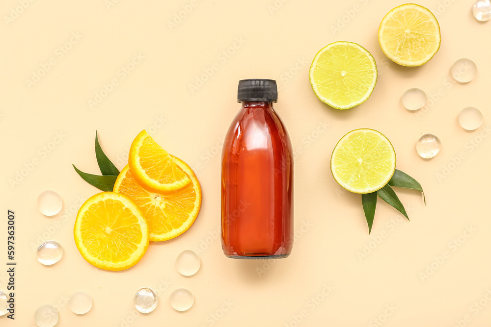 Bottle of cosmetic product with fruits slices and glass stones on beige background