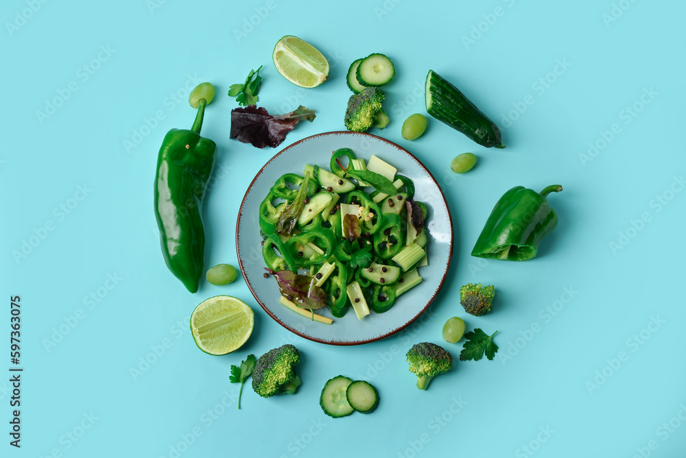 Plate with fresh salad and ingredients on turquoise background