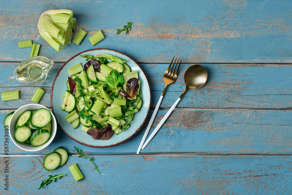 Plate of salad with vegetables and ingredients on blue wooden background