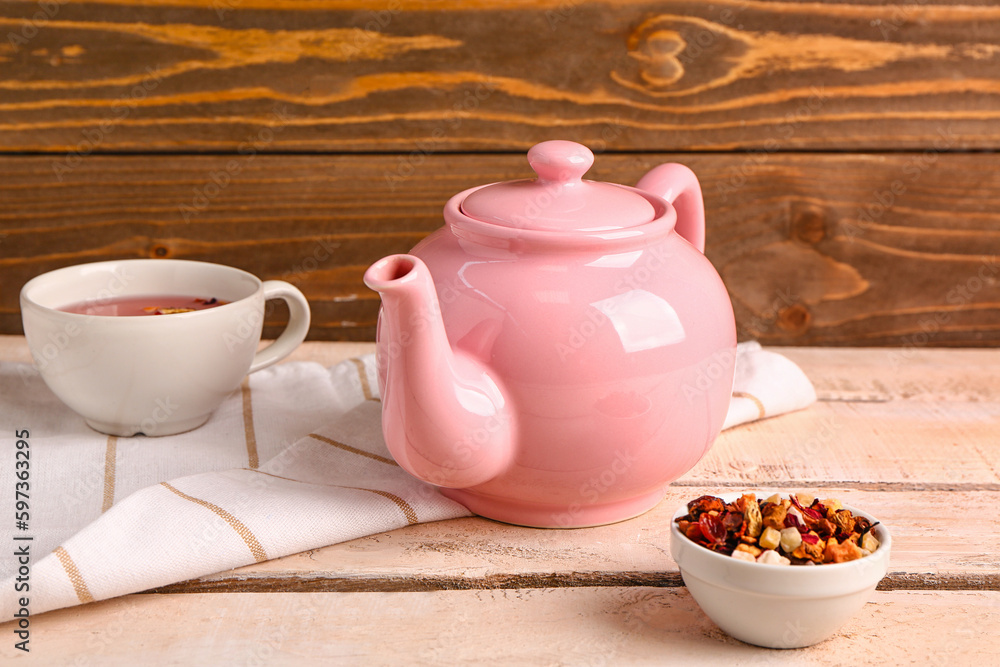 Ceramic teapot with cup of tea and dried fruits on white wooden table