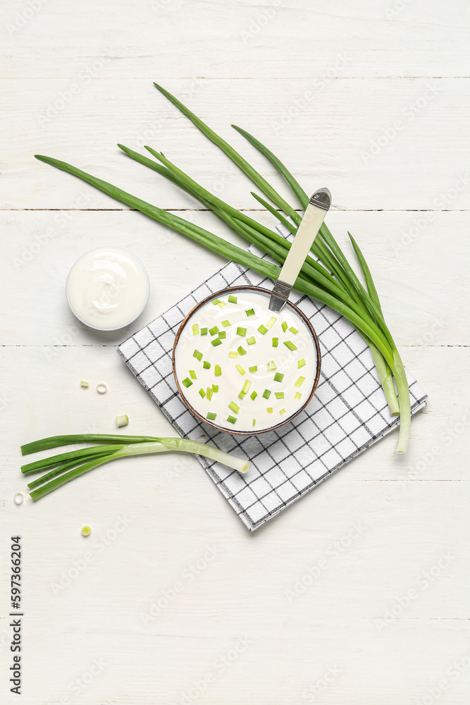 Bowls of tasty sour cream with green onion on light wooden background