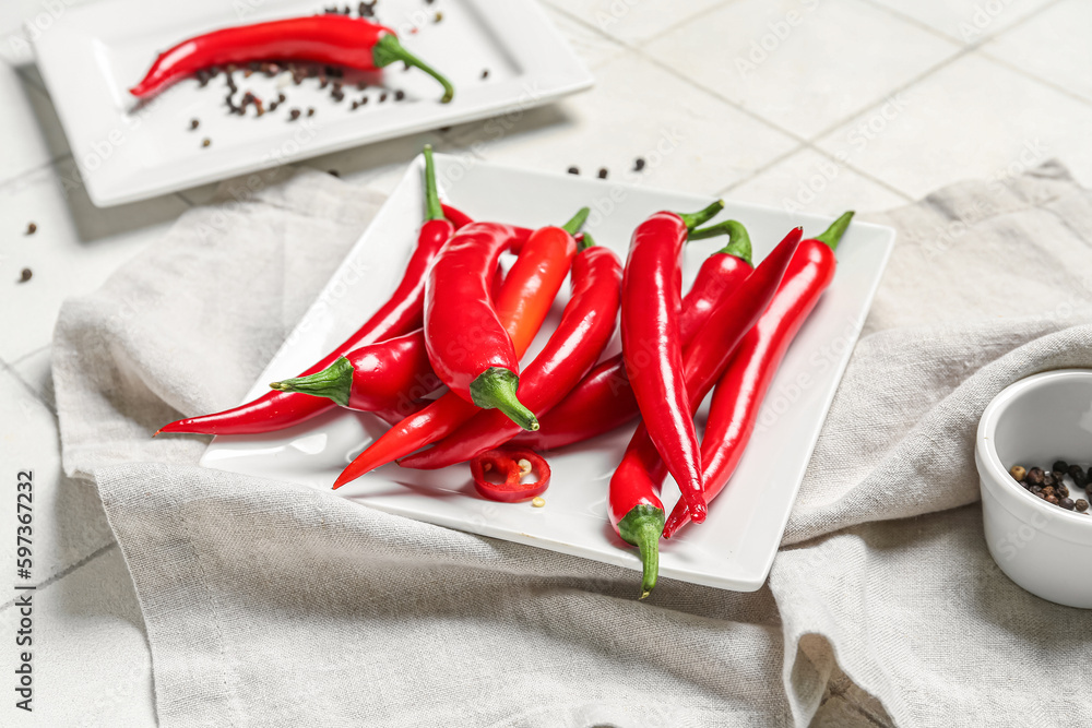 Plate with fresh chili peppers on table