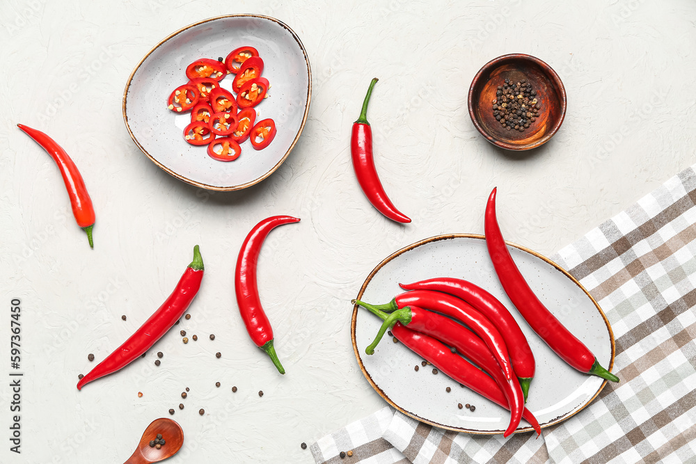 Plate and bowl with fresh chili peppers on light background