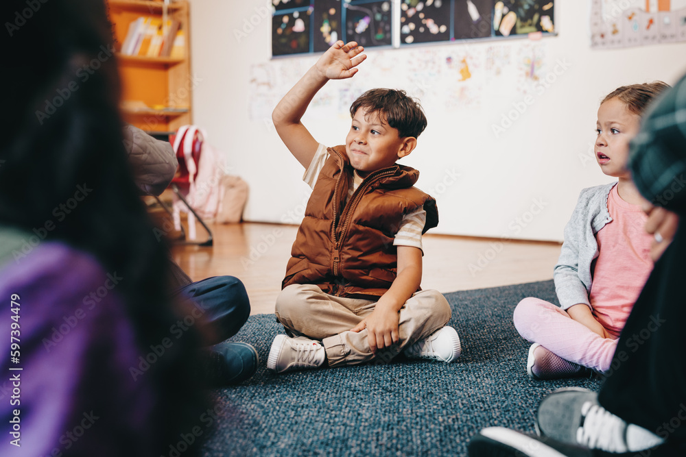 Smart elementary school kid raises his hand to give an answer in class