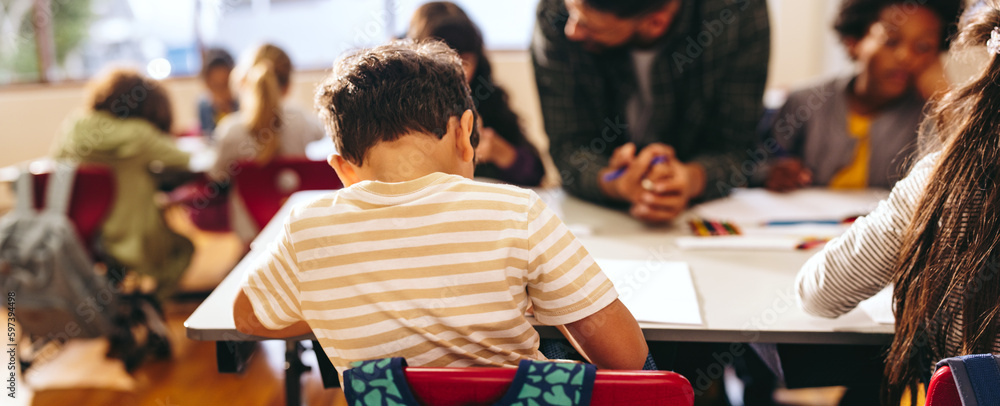 Rearview of a small boy doing his work in a primary school class