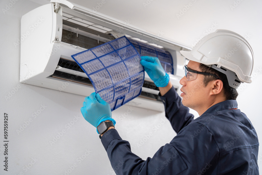 Air conditioner technician removes the air filter to clean the dust of the air conditioner on the wh