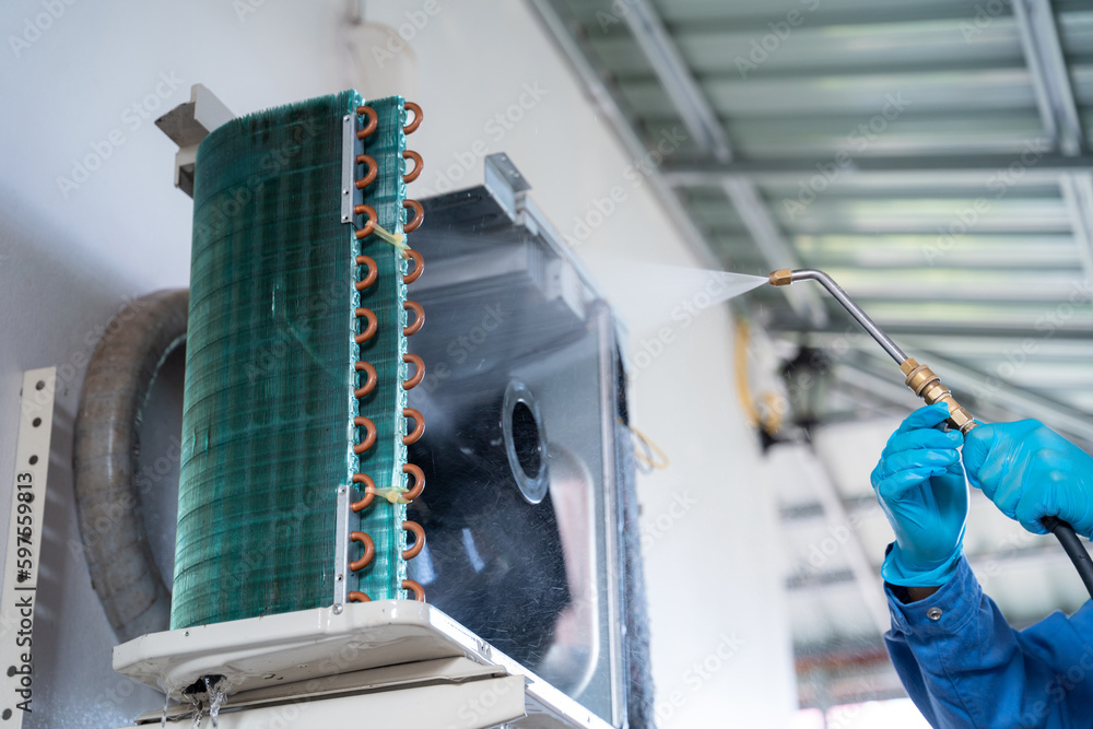 Close-up hand of air conditioner technician is using a high-pressure water jet to clean the air cond