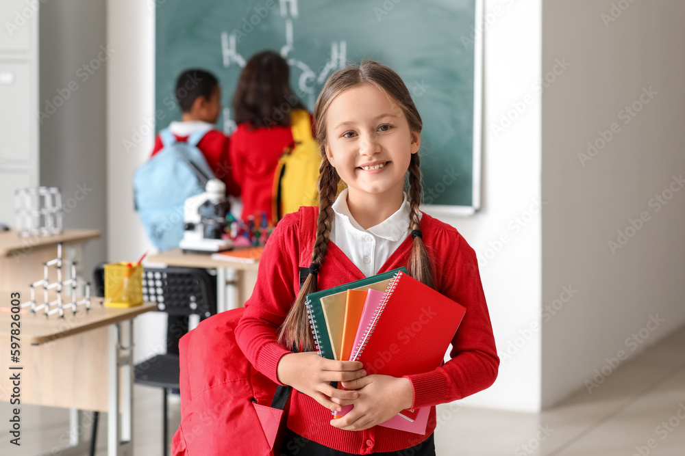 Little girl with notebooks in science classroom