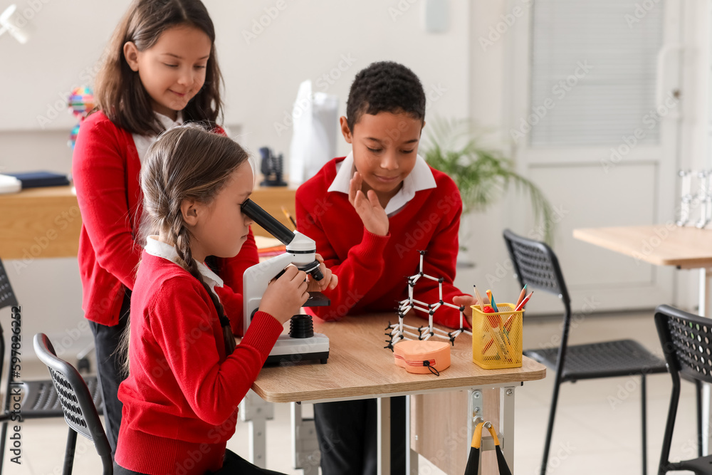 Little children with microscope having Chemistry lesson in science classroom