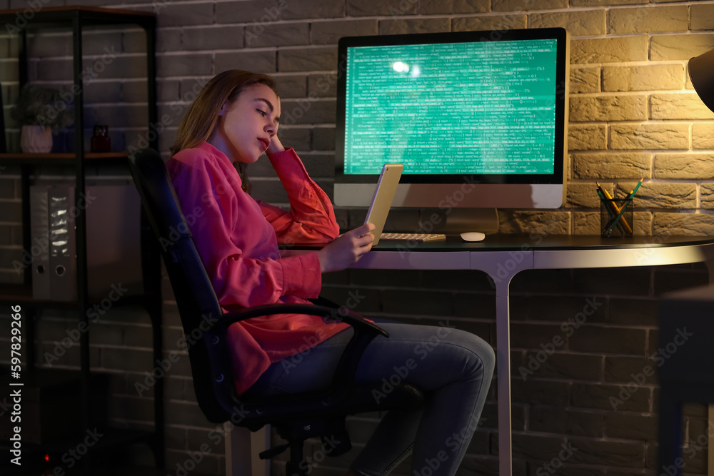 Female programmer working with tablet computer in office at night