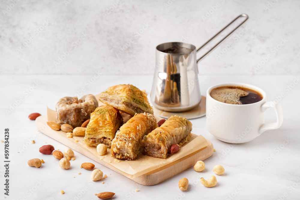 Wooden board with tasty baklava and cup of coffee on light background