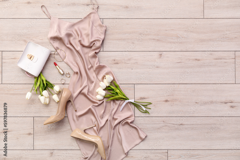 Silk dress with accessories, heels and tulips on light wooden floor