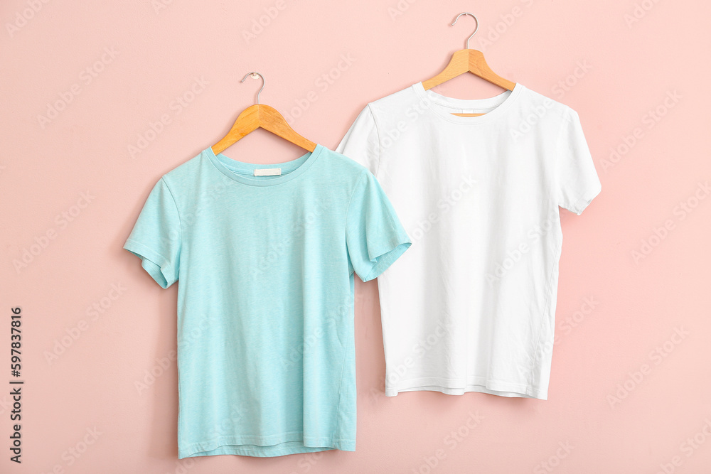 White and blue t-shirts hanging on pink wall