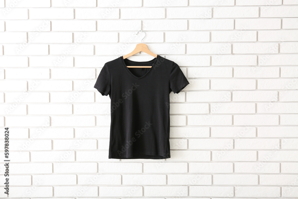 Black t-shirt hanging on white brick wall