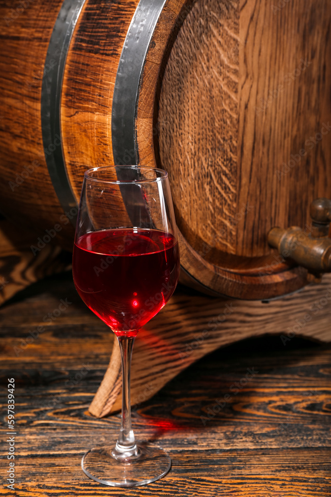 Oak barrel with glass of wine on wooden background