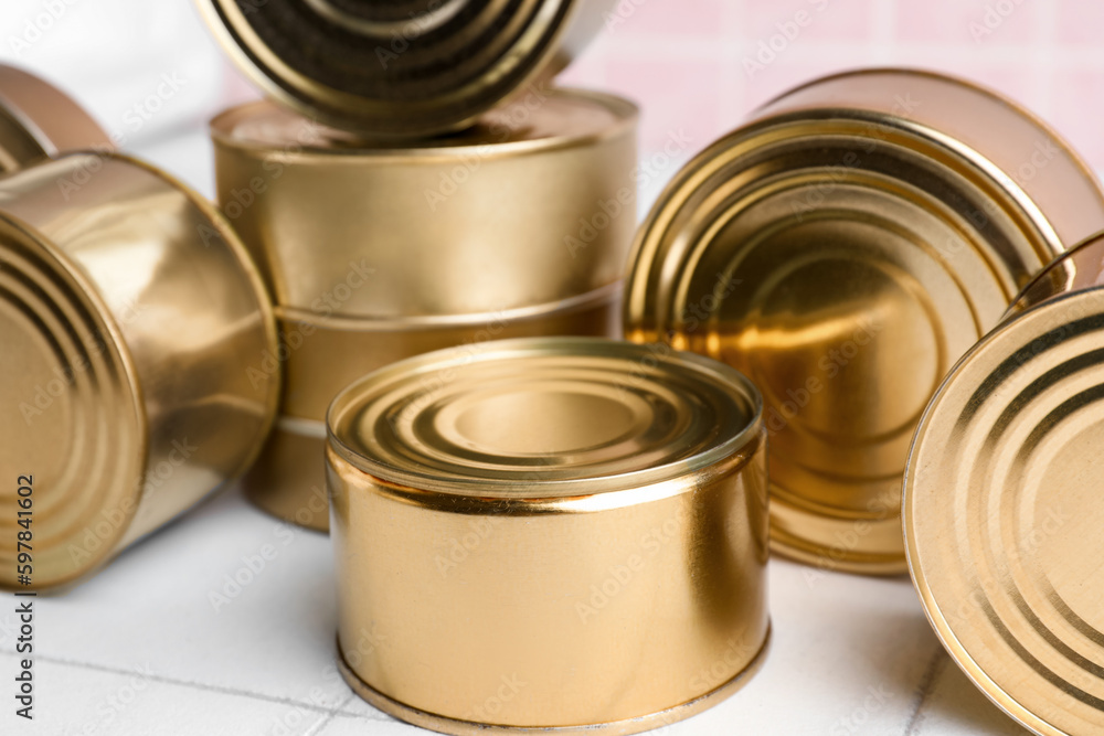 Tin cans with fish on white tiled table