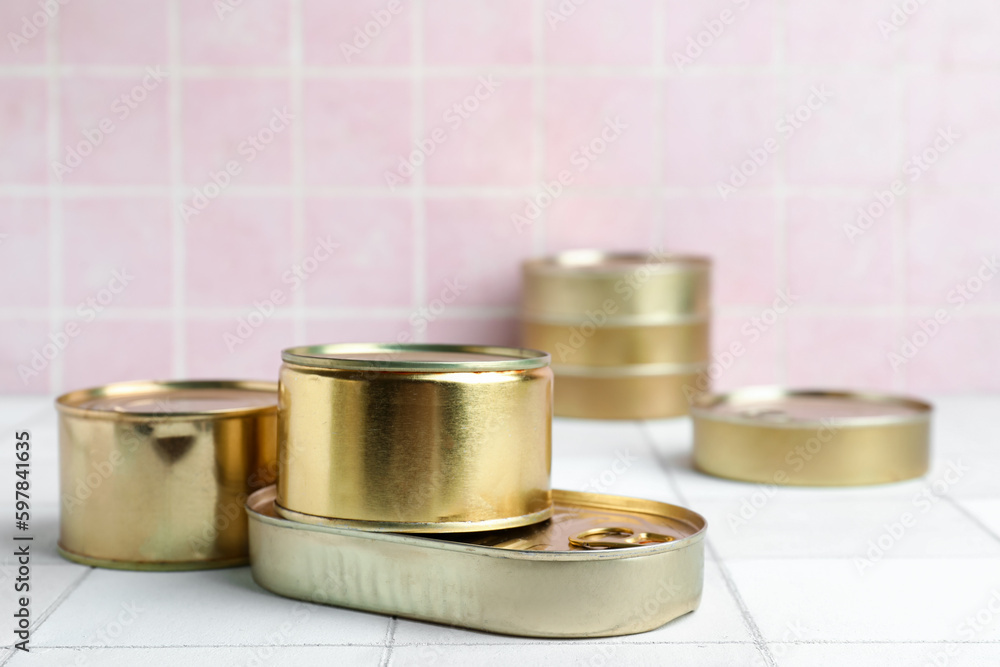 Tin cans with fish on white tiled table