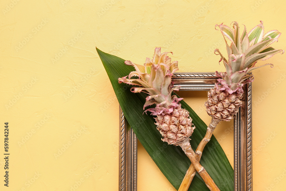 Decorative pineapples with palm leaf and frame on yellow background