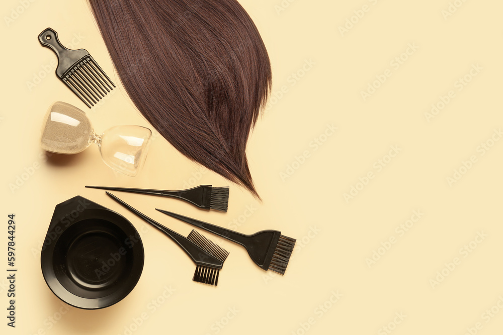 Brown hair with brushes, bowl and hourglass on beige background