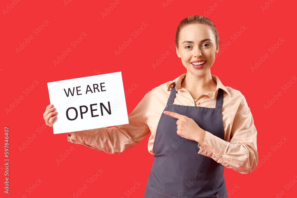 Young barista pointing at open sign on red background