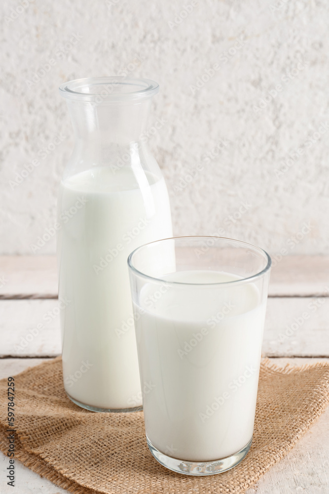 Bottle and glass with fresh milk on light wooden table