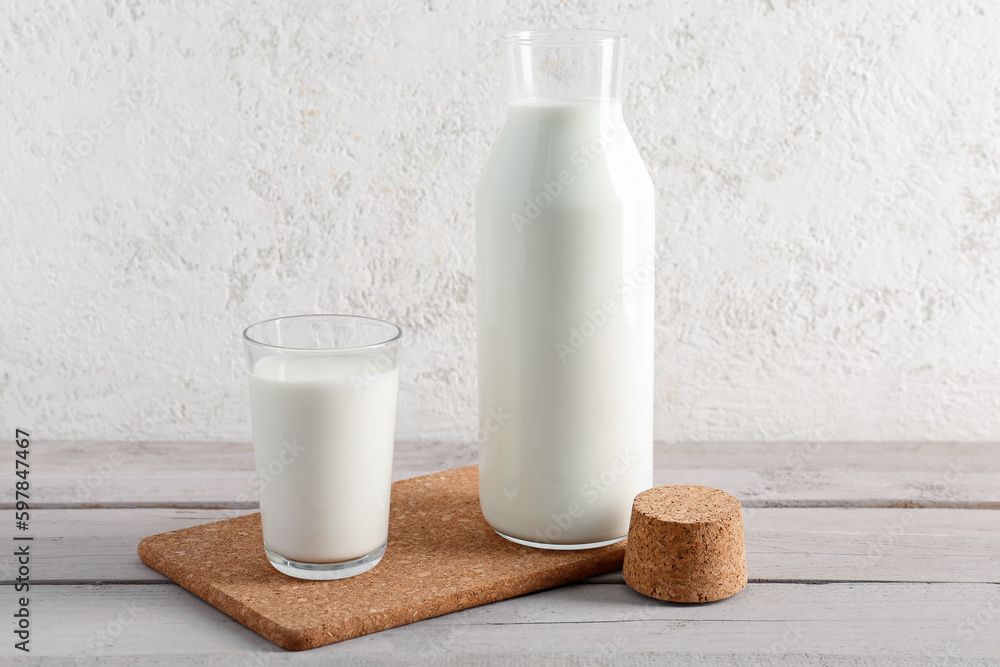 Bottle and glass with fresh milk on grey wooden table