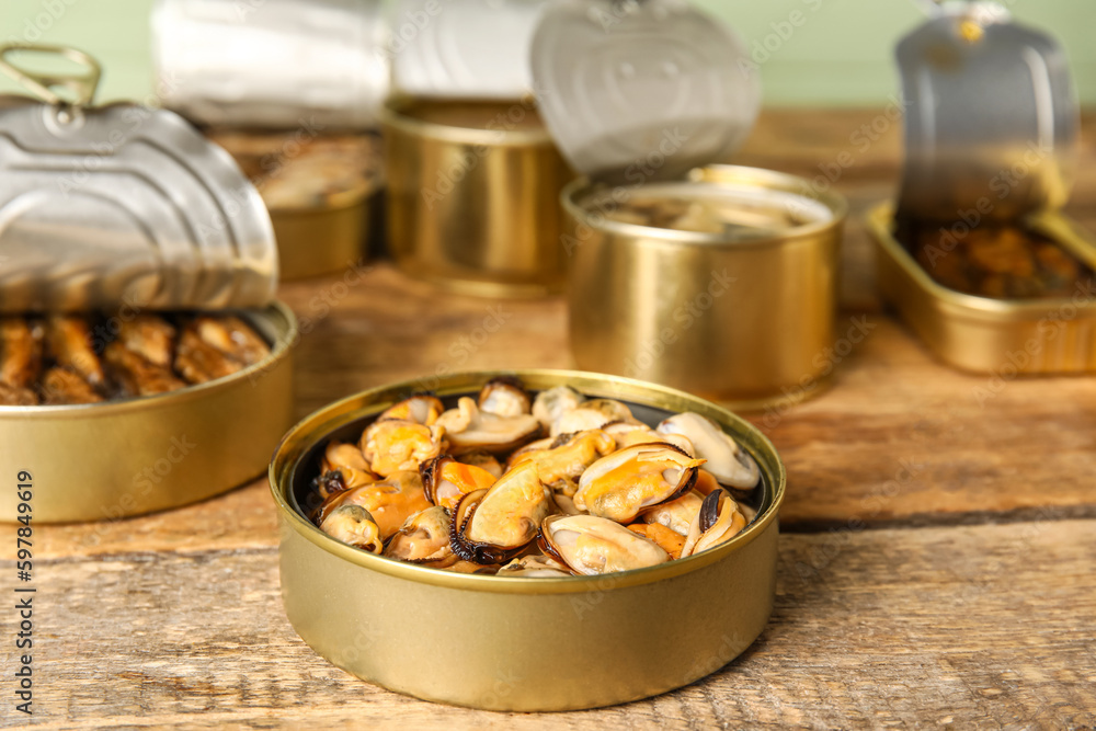 Opened tin can with mussels on wooden table